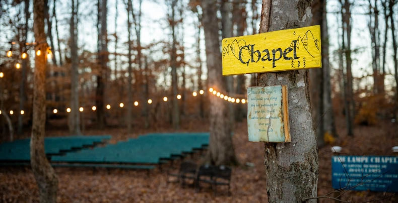 Wooded outdoor chapel along the prayer trail at Wings of Eagles Ranch, with string lights and seating creating a peaceful space for reflection and worship.