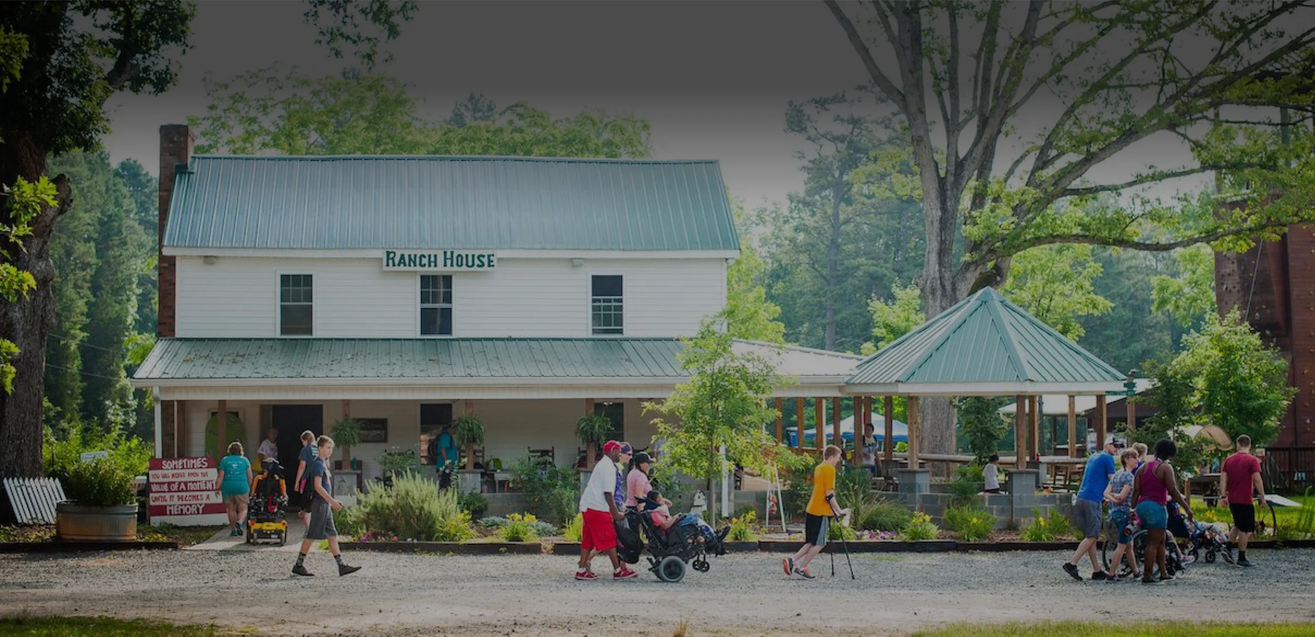Families and participants walking in front of the Ranch House at Wings of Eagles Ranch, an inclusive therapeutic riding and outdoor ministry center in North Carolina.